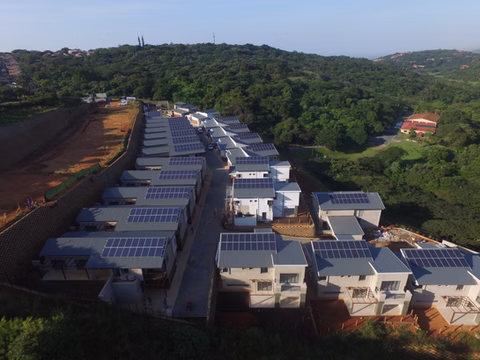 Residential units with solar panels on every roof, surrounded by trees