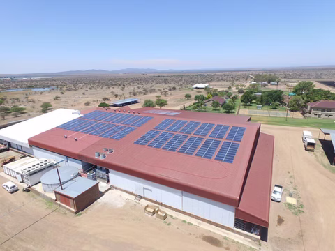 Solar panels on a red factory roof, seen from above